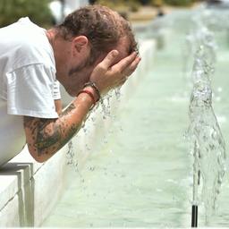 Ein Mann kühlt sich an einem Brunnen
