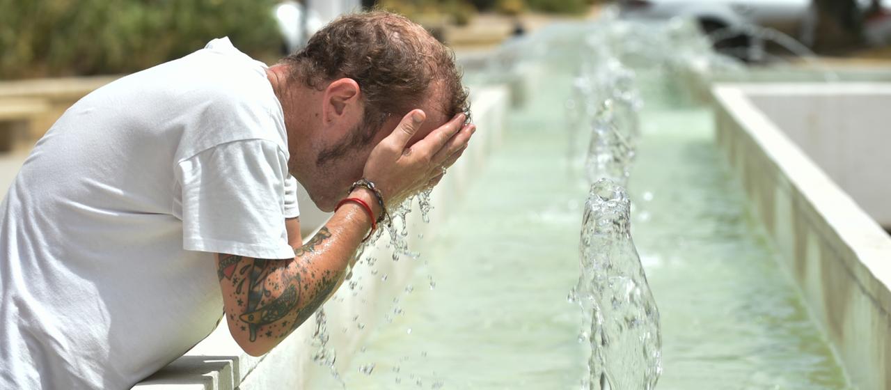 Ein Mann kühlt sich an einem Brunnen