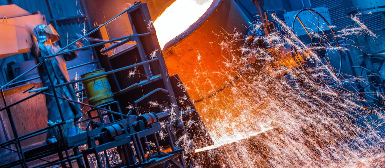 Ein Arbeiter in einem Schutzanzug arbeitet in einer Eisengießerei