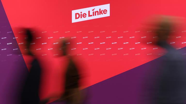 Schatten von Menschen, die an neuem Logo der Linkspartei vorbeigehen