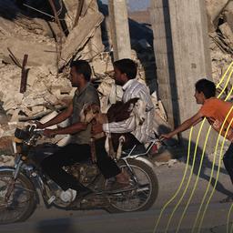 Syrer tragen zwei Ziegen auf einem Motorrad vor zerstörten Gebäuden südlich von Kobane, Syrien.