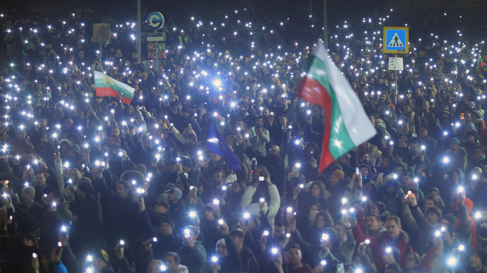 Demonstranten in Sofia zeigen ihre leuchtenden Handys und halten Fahnen | dpa
