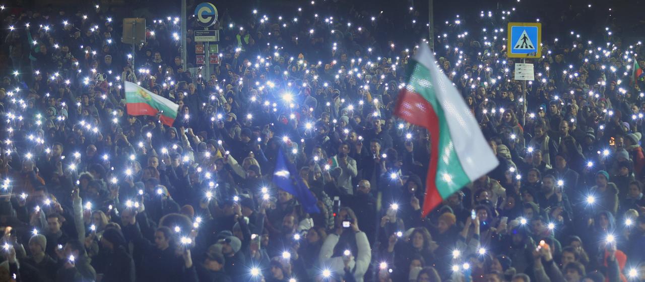 Demonstranten in Sofia zeigen ihre leuchtenden Handys und halten Fahnen
