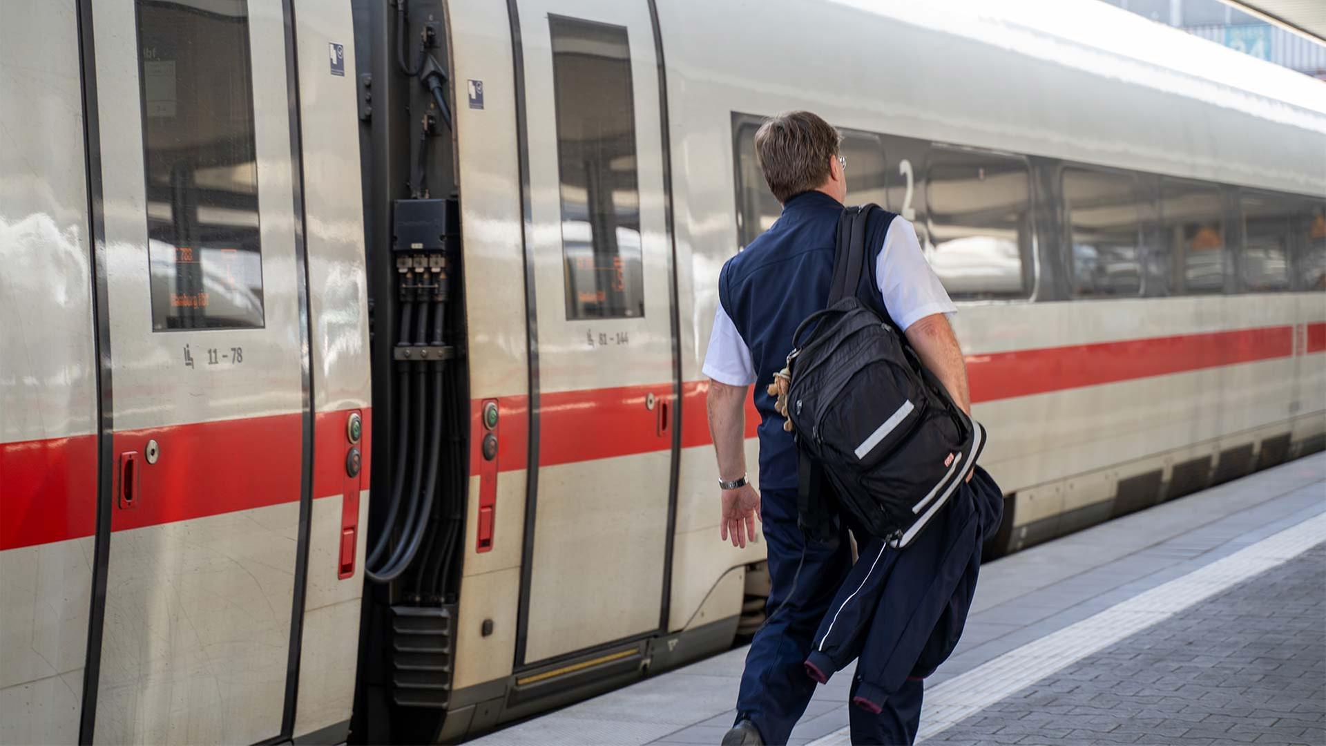 Ein Lokführer der Deutschen Bahn neben einem ICE. | picture alliance / DZBA