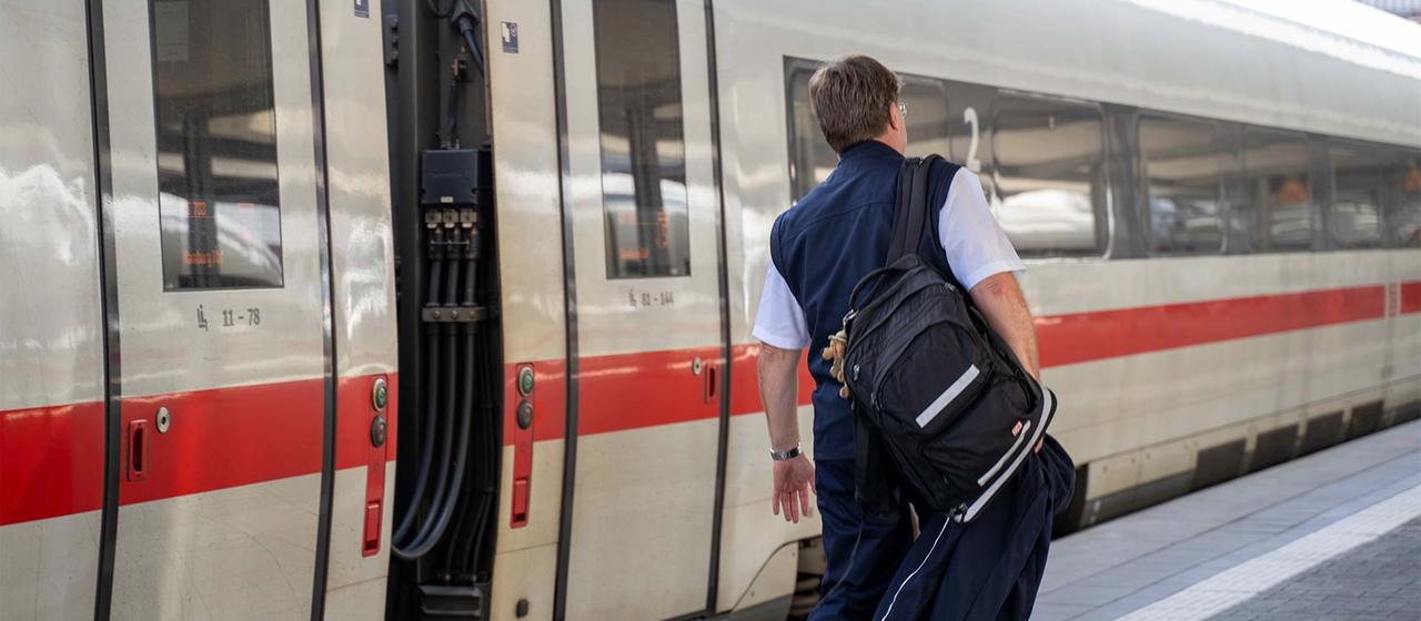 Ein Lokführer der Deutschen Bahn neben einem ICE.