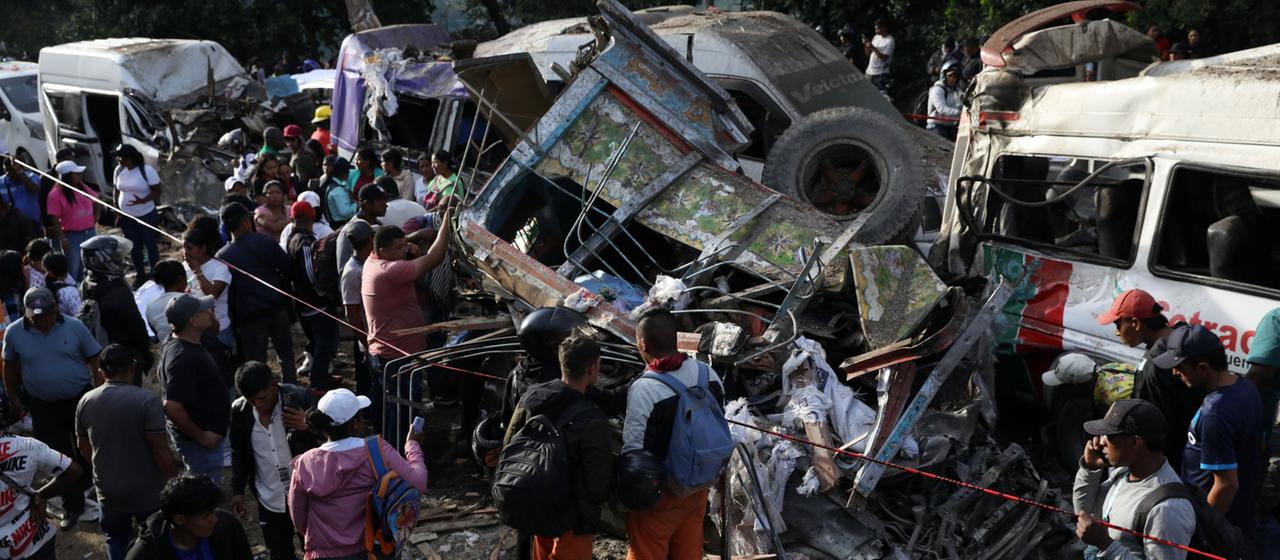 Menschen versammeln sich um Fahrzeuge, die bei einem Anschlag In Kolumbien beschädigt wurden