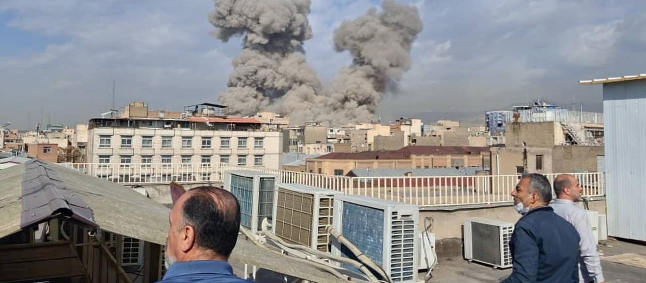 Menschen beobachten Rauchsäulen nach einer Explosion in Teheran.