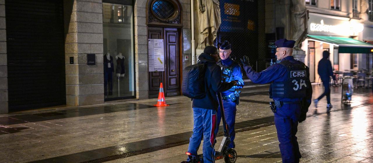 Polizisten kontrollieren einen Passanten während der Ausgangssperre in Lyon