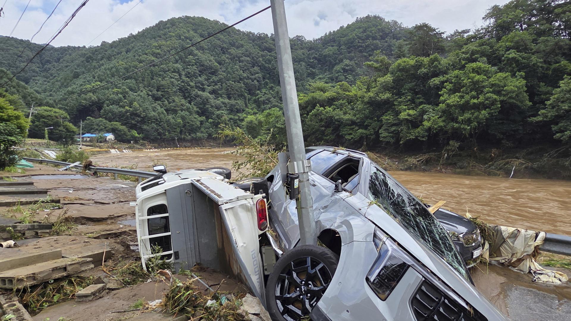 Ein Auto ist nach einem Erdrutsch in Südkorea an einem Mast hängen geblieben. | dpa