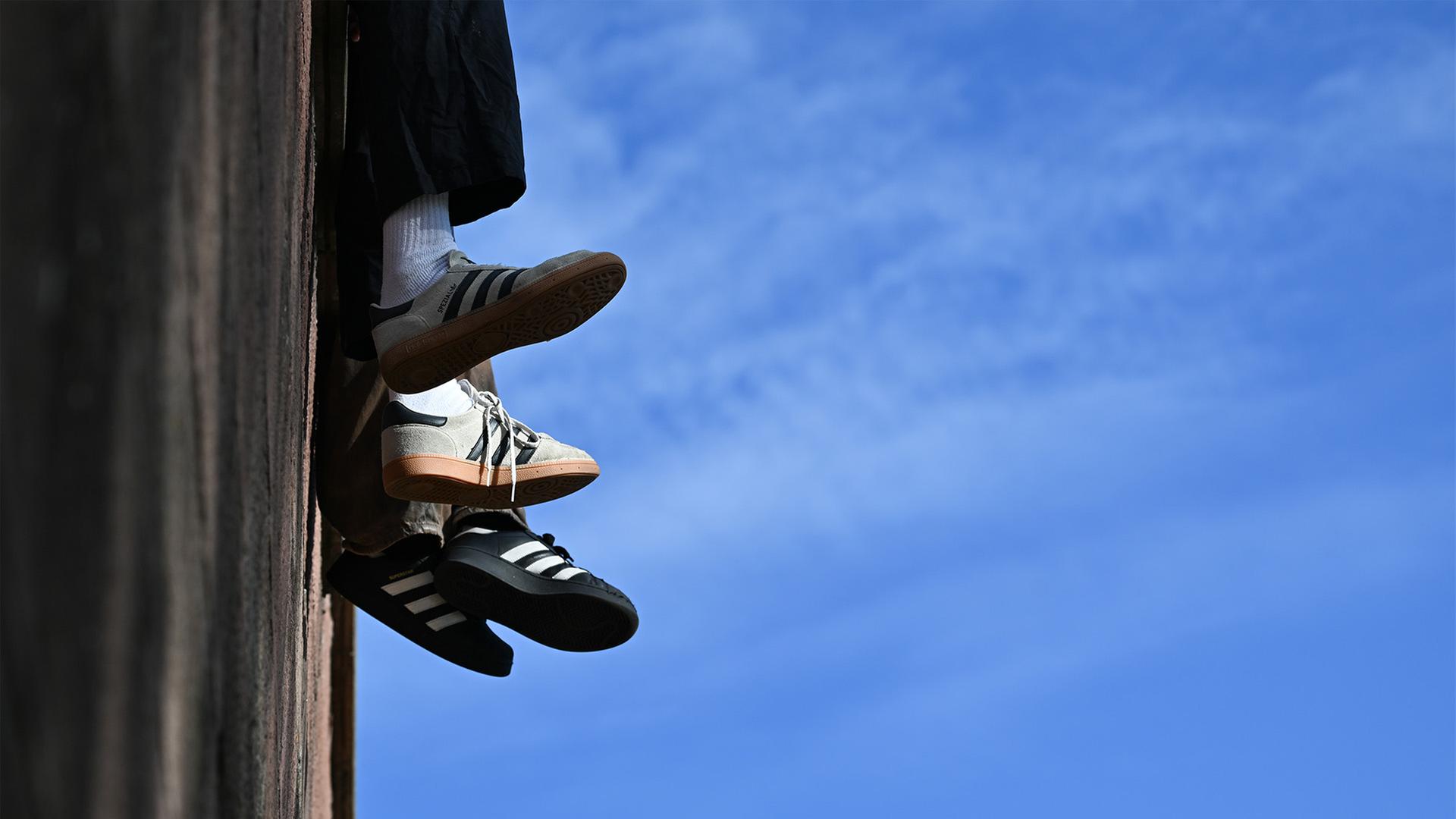 Schuhe von jungen Menschen die auf einer Mauer sitzen | dpa