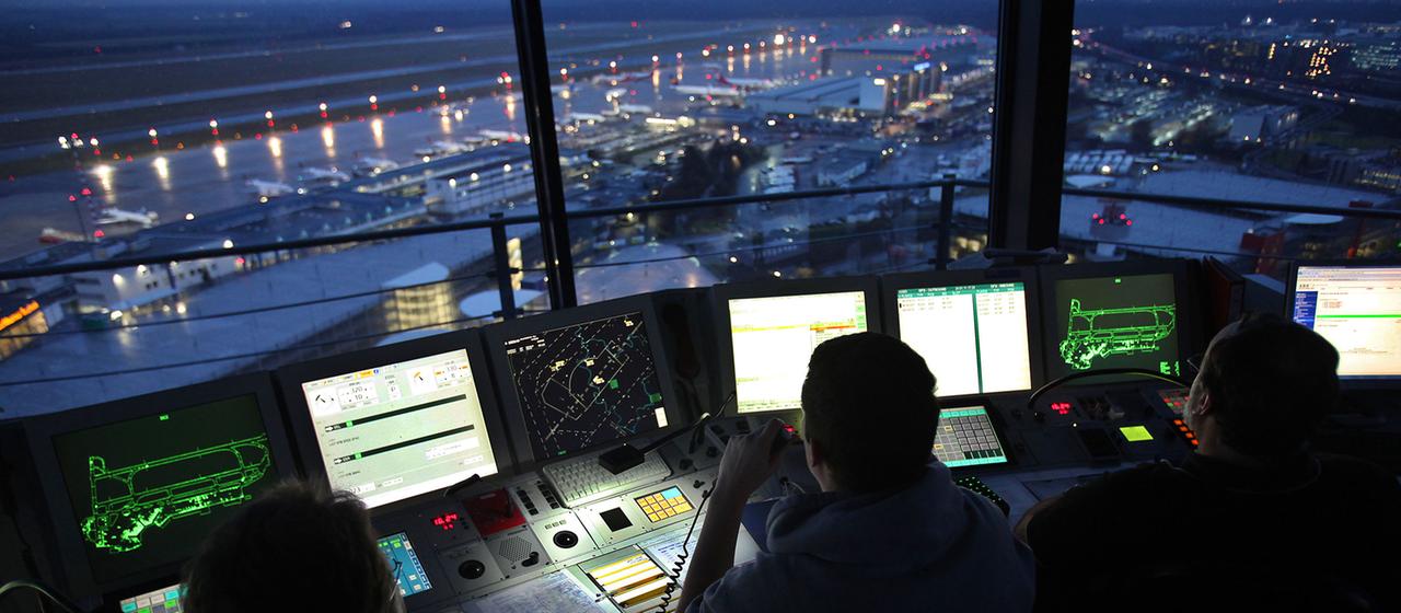 Fluglotsen arbeiten am Flughafen Düsseldorf bei Nacht.