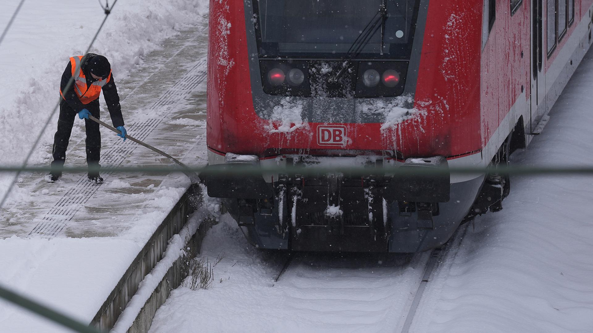 Ein Mitarbeiter beseitigt eine dicke Schneeschicht auf einem Bahnsteig. | dpa