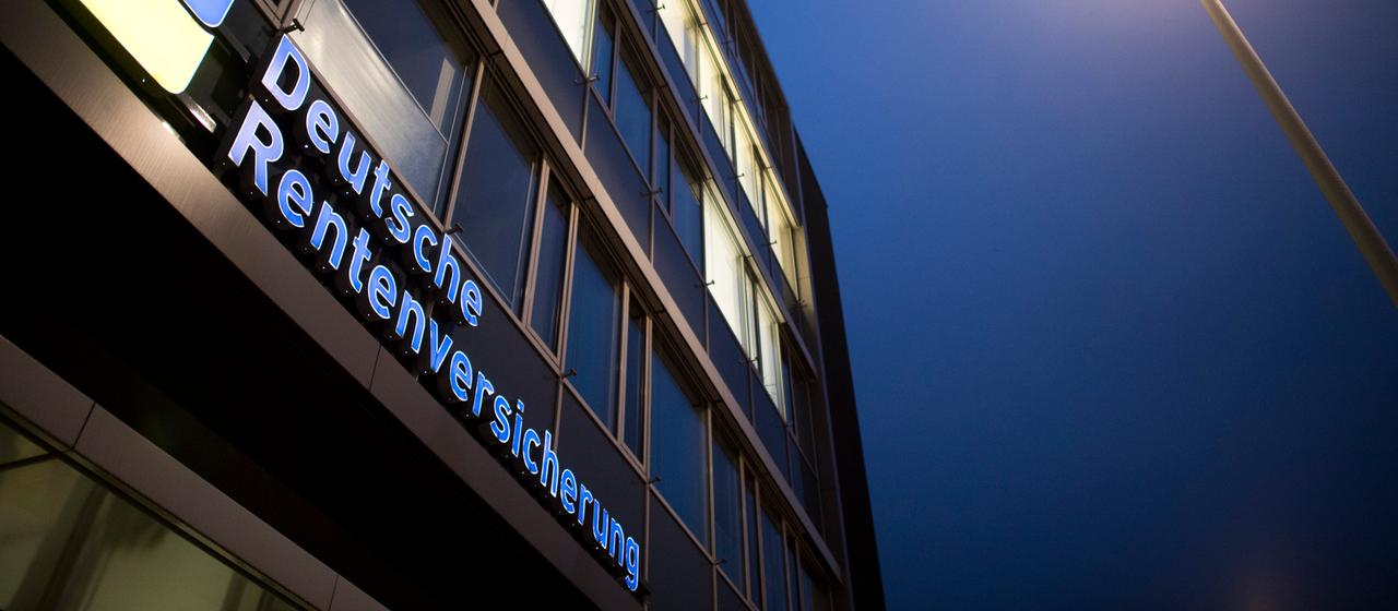 Logo der Deutschen Rentenversicherung leuchtet an einem Gebäudeeingang