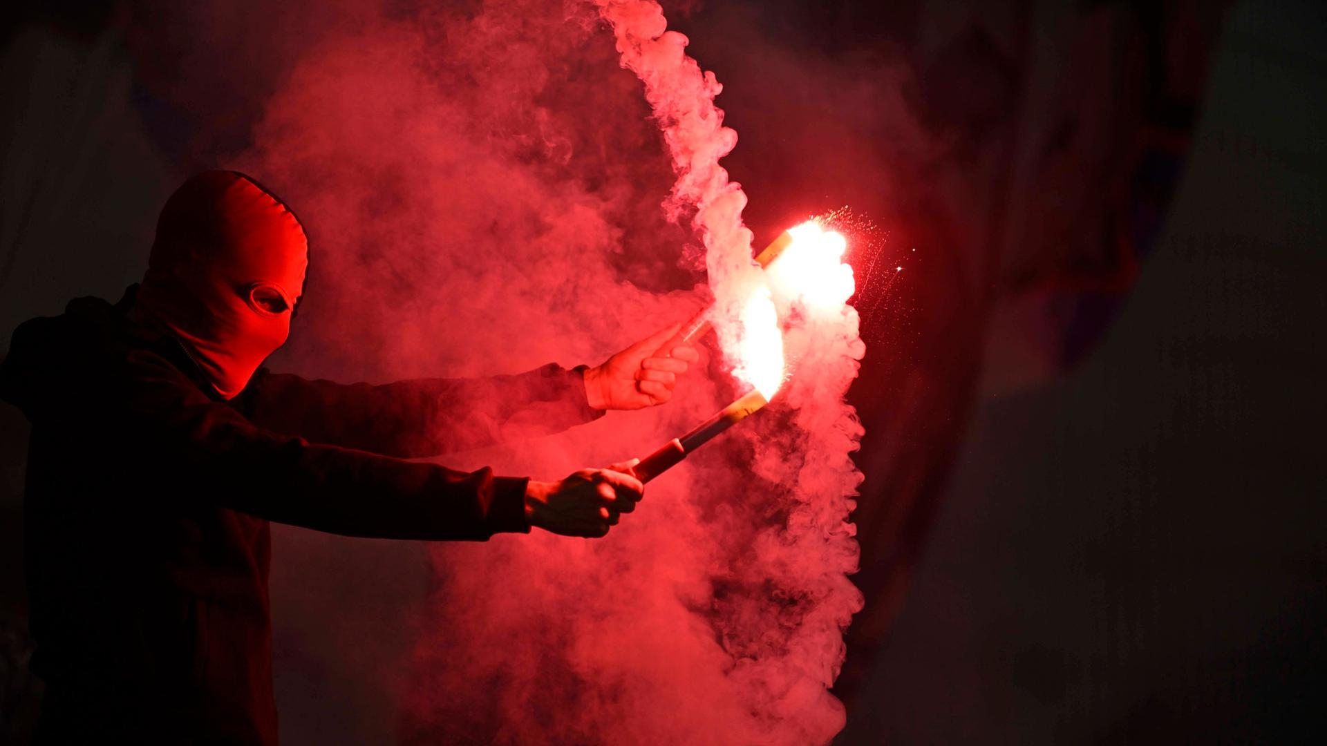 Zwei Hände halten rote Bengalo-Fackeln - von Qualm umgeben | Imago/MIS