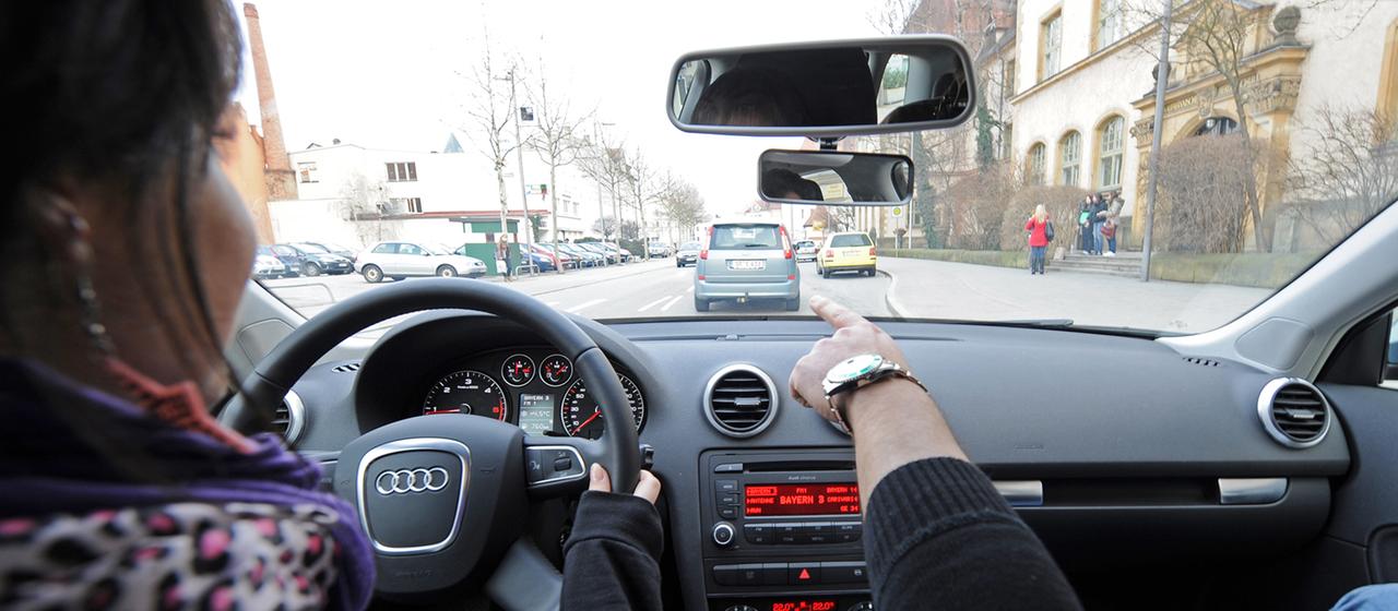 Eine 17-jährige Fahrschülerin und ihr Fahrlehrer sitzen in einem Fahrschulauto.