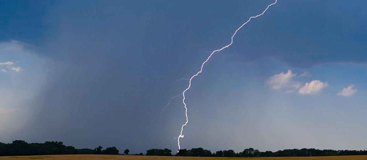 Ein Blitz leuchtet vor dunklen Gewitterwolken über der Landschaft im östlichen Brandenburg (ARCHIV, 28.06.2026).