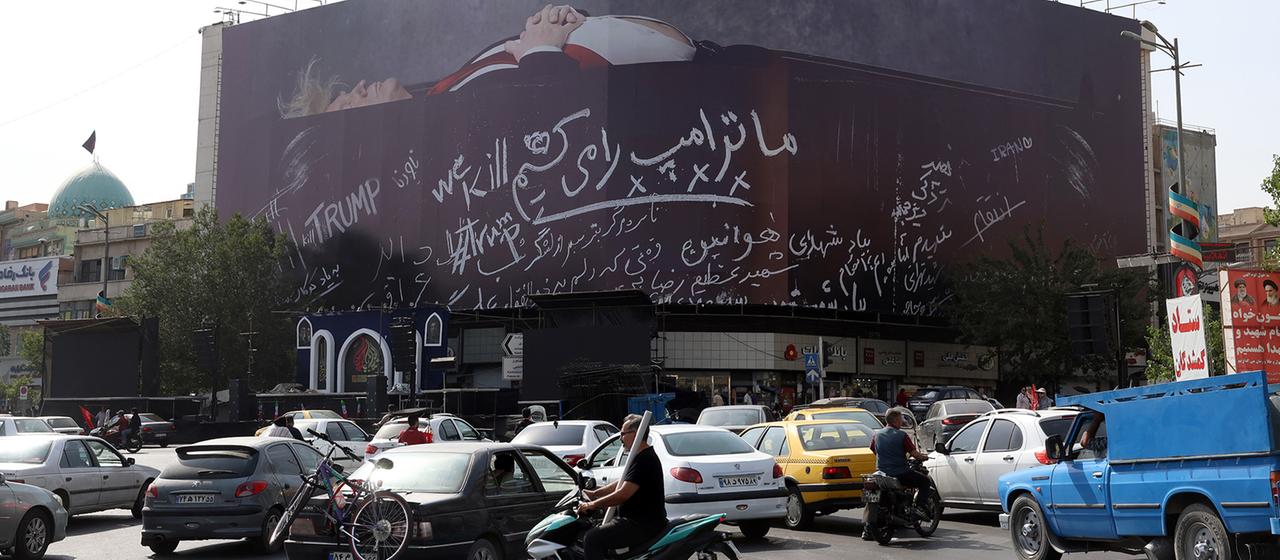 Iraner fahren am Enghelab-Platz in Teheran im Iran an einer Anti-USA-Plakatwand vorbei, die US-Präsident Donald Trump in einem Sarg sowie den Slogan "Wir töten Trump" zeigt.