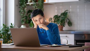 Eine Frau arbeitet am Laptop in der Küche.