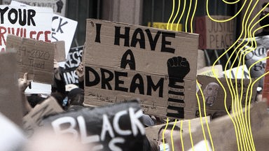 Inmitten eines Meeres aus Plakaten einer Demonstration befindet sich eines mit dem Titel einer Rede von Martin Luther King I have a dream