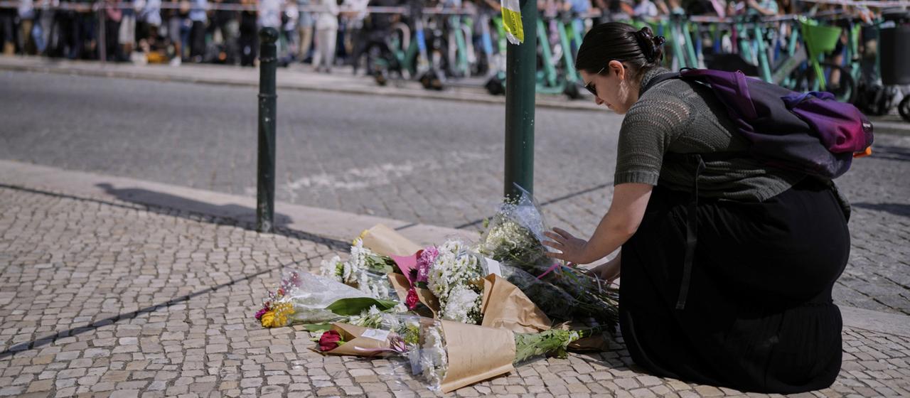 Eine Frau legt Blumen nahe dem Standseilbahn-Unglücksort in Lissabon nieder 
