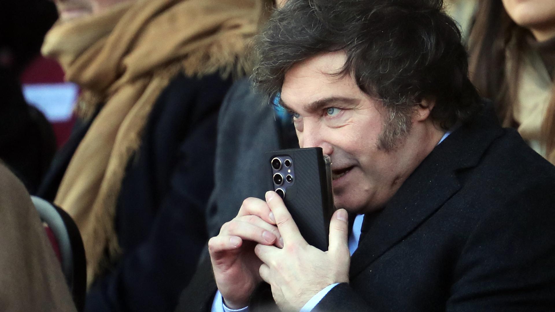 Javier Milei hält sich ein Smartphone vor den Mund. | AFP