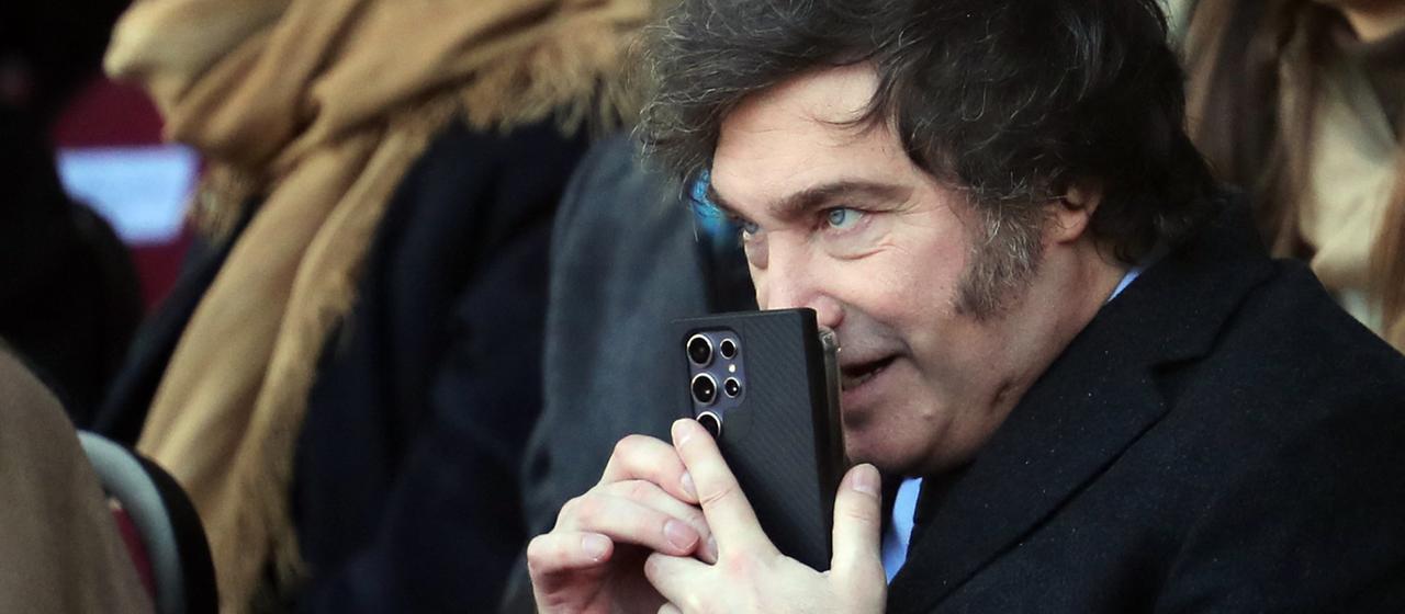 Javier Milei hält sich ein Smartphone vor den Mund.