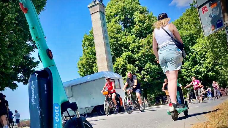 Menschen fahren mit Fahrrädern und E-Scootern über einen Weg.