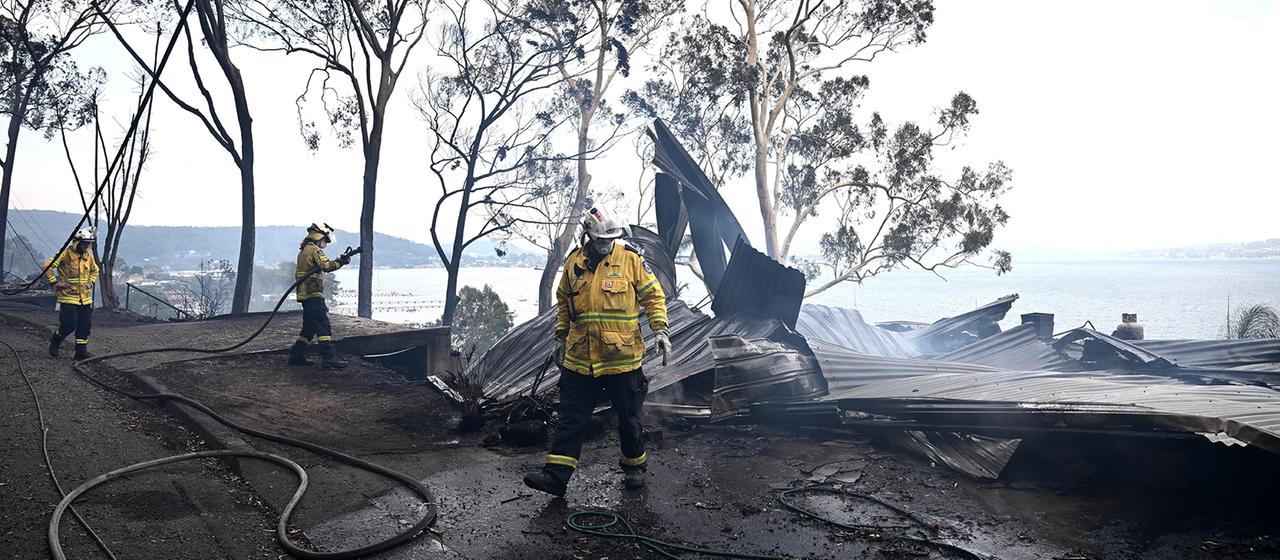 Feuerwehrkräfte bei Löscharbeiten an Häusern.