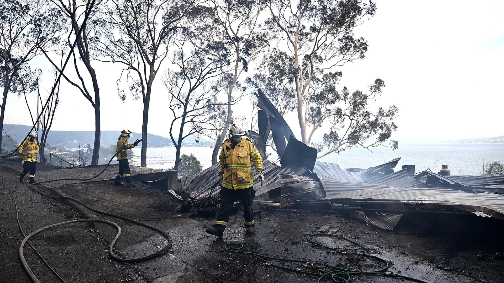 Feuerwehrkräfte bei Löscharbeiten an Häusern. | EPA