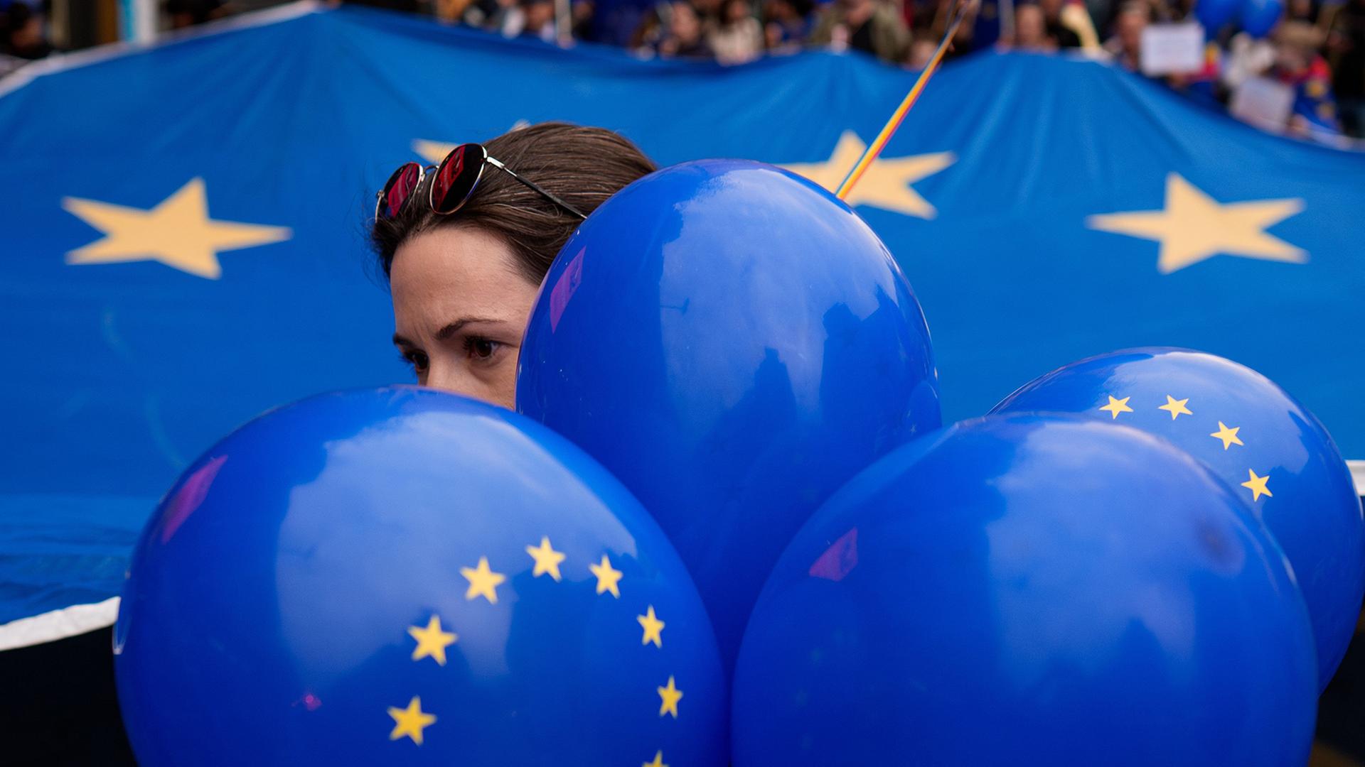 Eine Frau mit blauen Luftballons vor einer Flagge der Europ�ischen Union. | AP