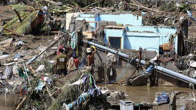 Anwohner der phillipinischen Provinz Cebu laufen durch Trümmer, die Taifun "Kalmaegi" verursacht hat.