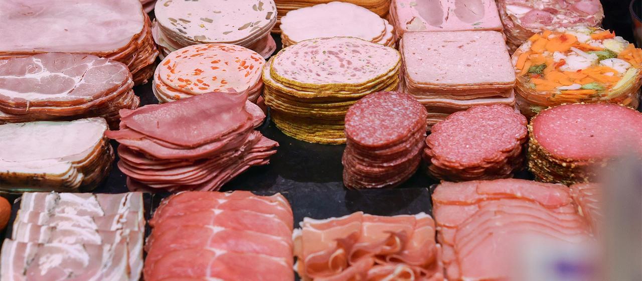 Wurst und Schinken liegen in der Kühltheke einer Fleischerei.