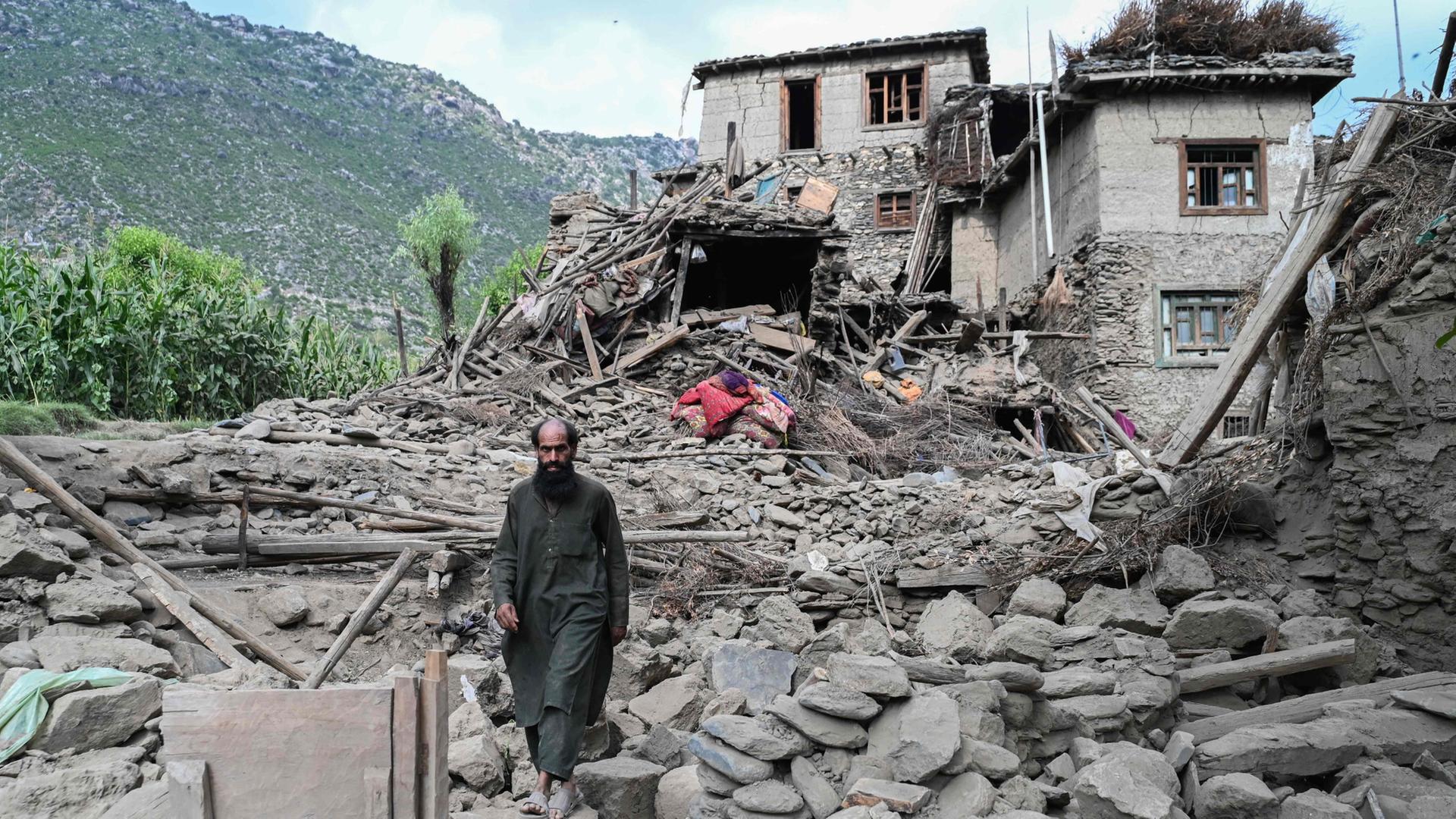 Ein afghanischer Mann geht an einem nach Erdbeben beschädigten Haus im Dorf Nurgal in Mazar Dara, einem Bezirk der Provinz Kunar, vorbei. | AFP