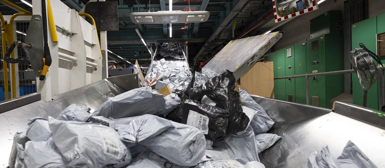 Ein Berg an Postsendungen liegt auf einem Förderband.