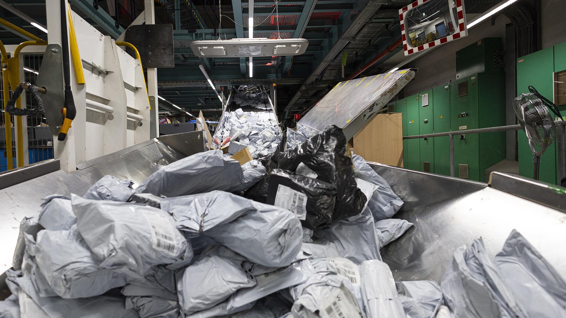 Ein Berg an Postsendungen liegt auf einem Förderband. | dpa