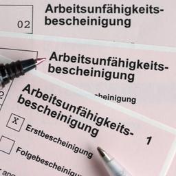 Stifte liegen auf einem Stapel von Arbeitsunfähigkeitsbescheinigungen für Arbeitnehmer 