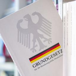 Ein Buch "Grundgesetz" ragt schräg aus einem Regal.