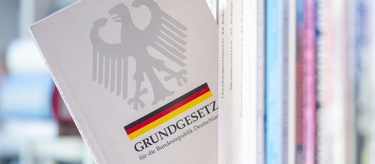 Ein Buch "Grundgesetz" ragt schräg aus einem Regal.