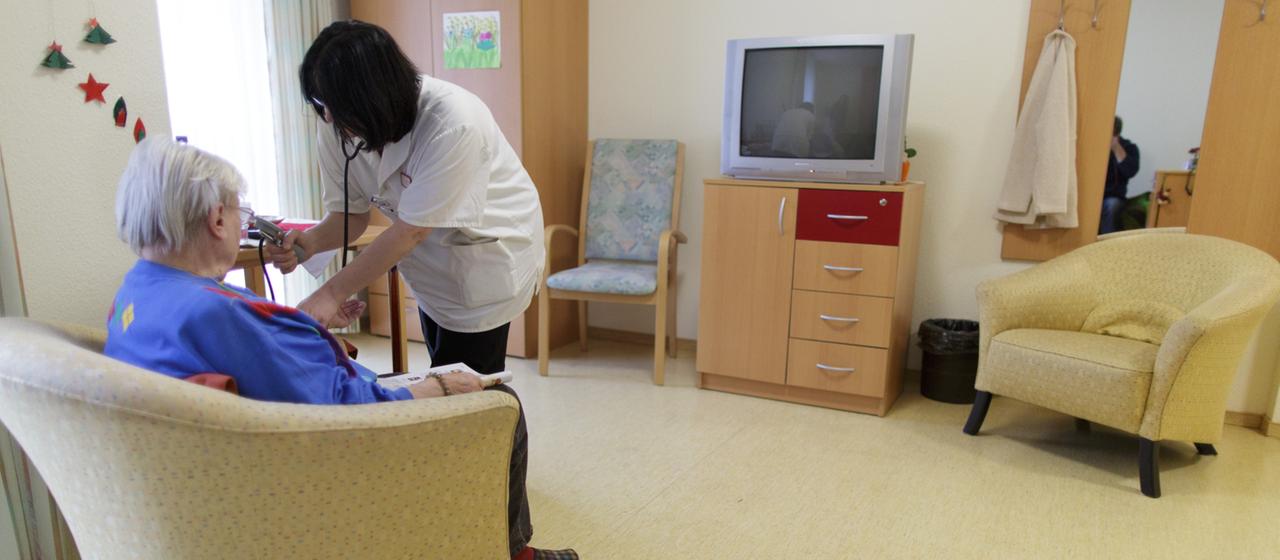 Eine Pflegerin untersucht eine Seniorin in einem Pflegeheim.