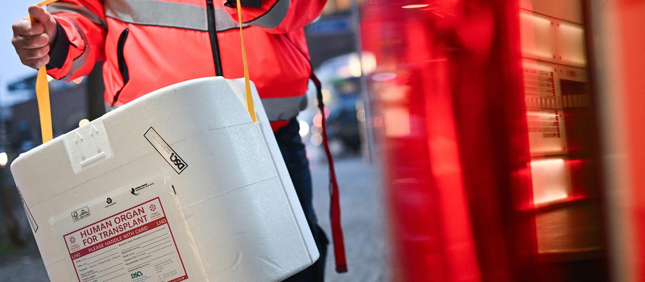 Ein Mitarbeiter der Malteser stellt eine Kühlbox für eine Organspende in einen Transporter