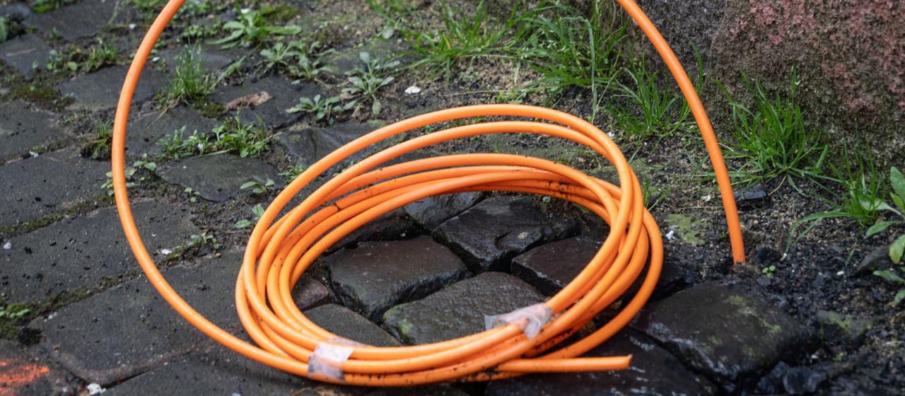 Ein aufgerolltes Glasfaserkabel kommt aus der Erde