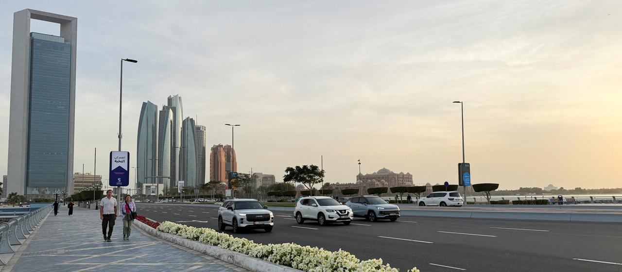 People walk on a promenade overlooking the skyline of Abu Dhabi, United Arab Emirates.