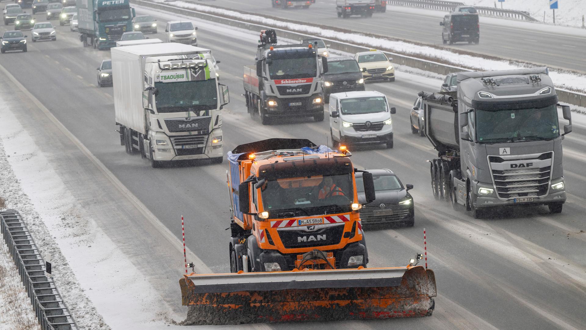 Ein Schneeräufahrzeug, Autos und Lastwagen fahren bei Schneefall auf der Autobahn A9 im Norden von München. | dpa