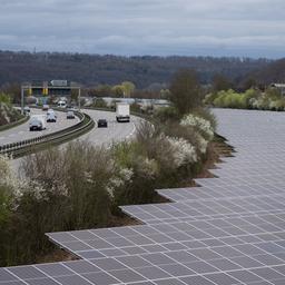 Solarpaneele stehen neben einer Autobahn.
