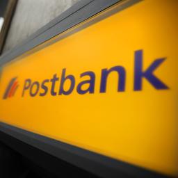 Ein Mann geht in Köln (Nordrhein-Westfalen) an einer Filiale der Post und Postbank vorbei