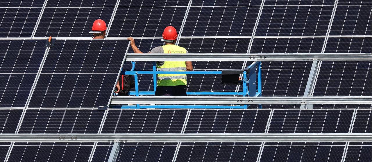 Mitarbeiter einer Montagefirma montieren Solarmodule in einem Solarpark.