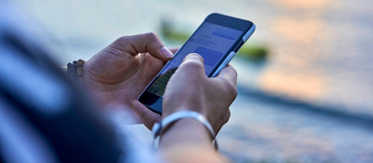 Hände benutzen ein Smartphone.