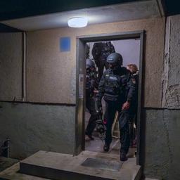 Polizisten verlassen während einer Wohnungsdurchsuchung ein Haus.