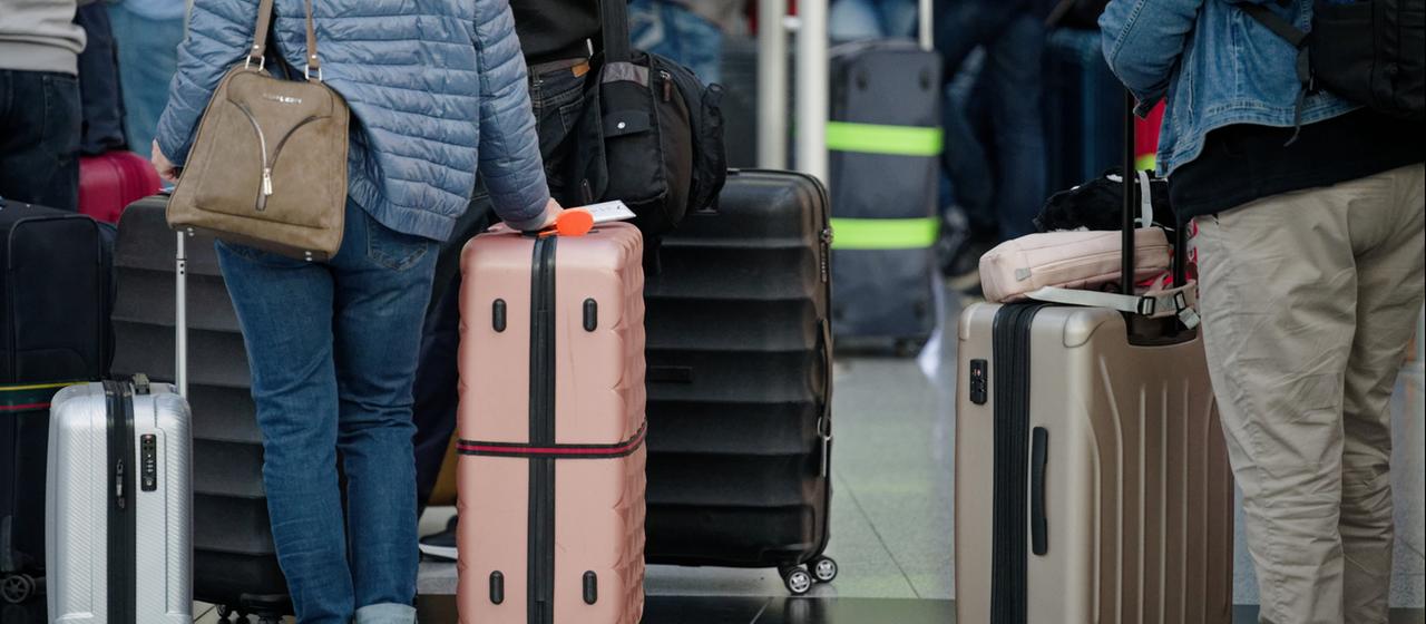 Fluggäste stehen in der Abflughalle im Flughafen Düsseldorf mit ihrem Gepäck.