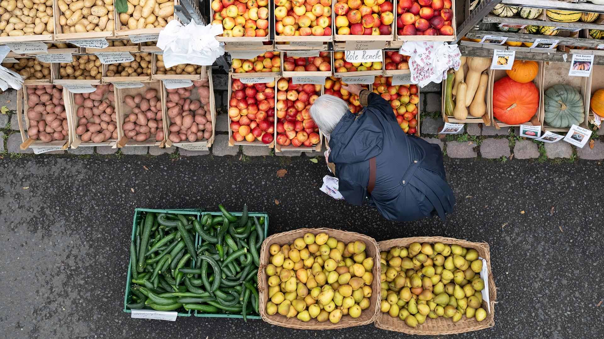 Eine Frau steht auf einem Wochenmarkt an einem Stand mit Obst und Gemüse. | dpa